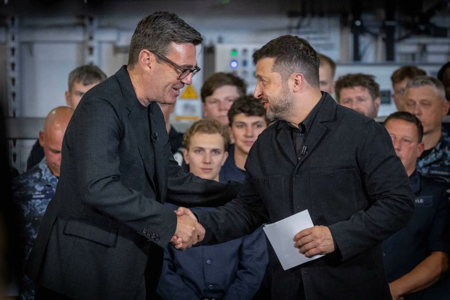 British Prime Minister Andy Burnham shakes hands with Ukrainian President Volodymyr Zelensky in front of a group of Ukrainian servicemembers.