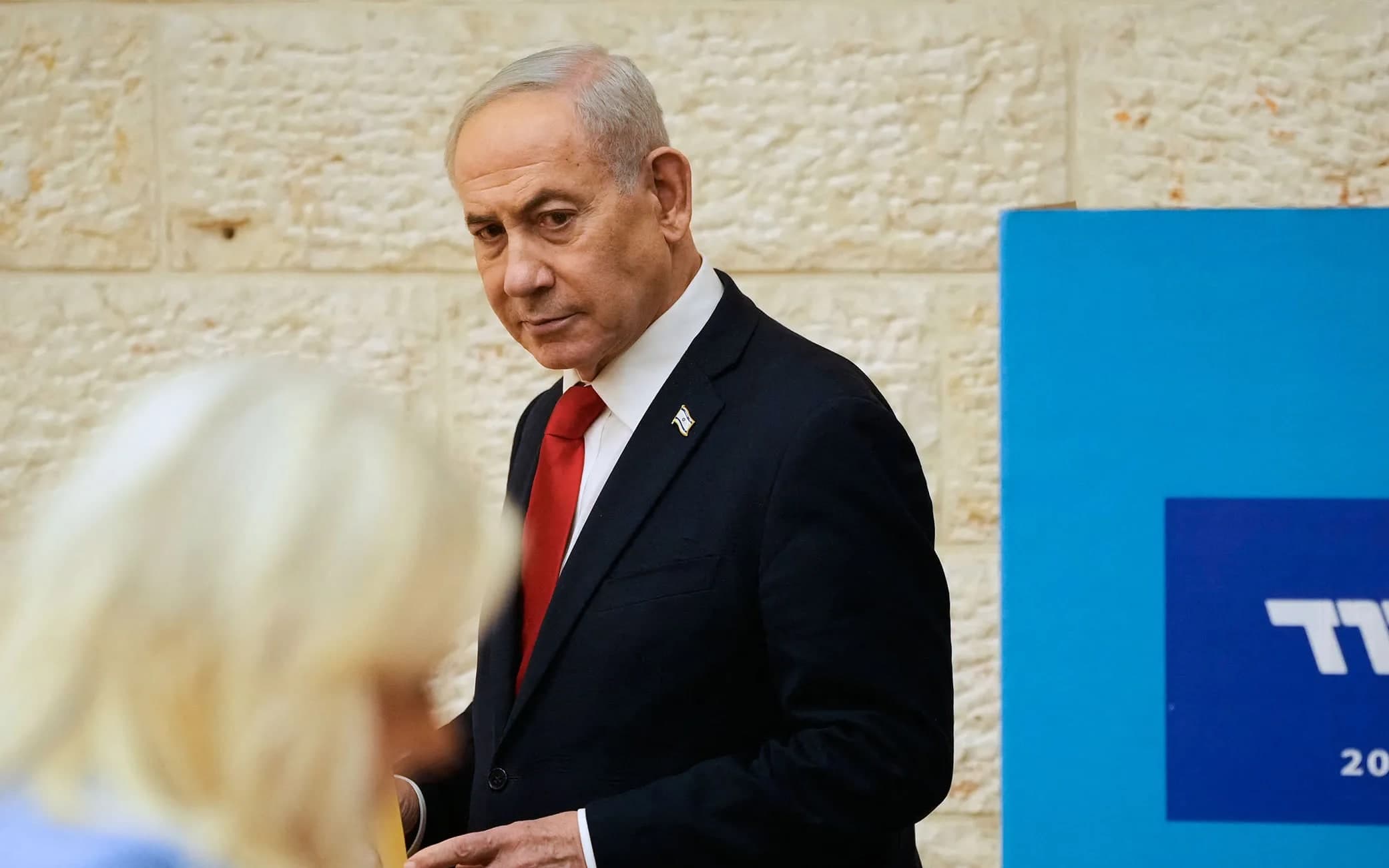 Benjamin Netanyahu walking past a blurred figure in the foreground