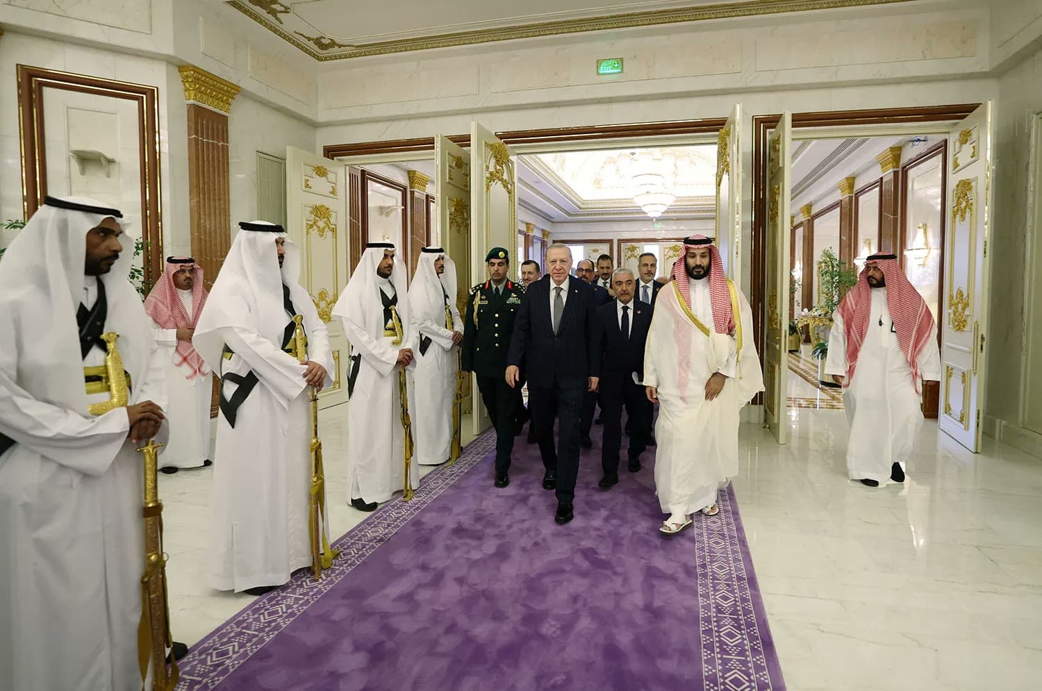 Turkish President Recep Tayyip Erdogan walks alongside Saudi Crown Prince Mohammed bin Salman down a marble hallway lined with an honor guard in Mecca.