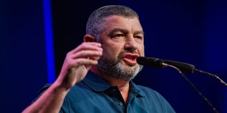 Ofer Winter speaking into a microphone with an intense expression