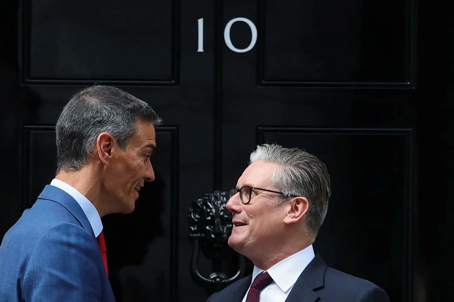Spanish Prime Minister Pedro Sanchez and British Prime Minister Keir Starmer speak face to face outside the black door of 10 Downing Street.